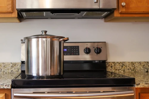 A large stainless steel cooking pot on a stove in a home kitchen.